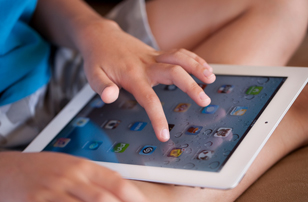 A child's hand selects an app on the iPad.