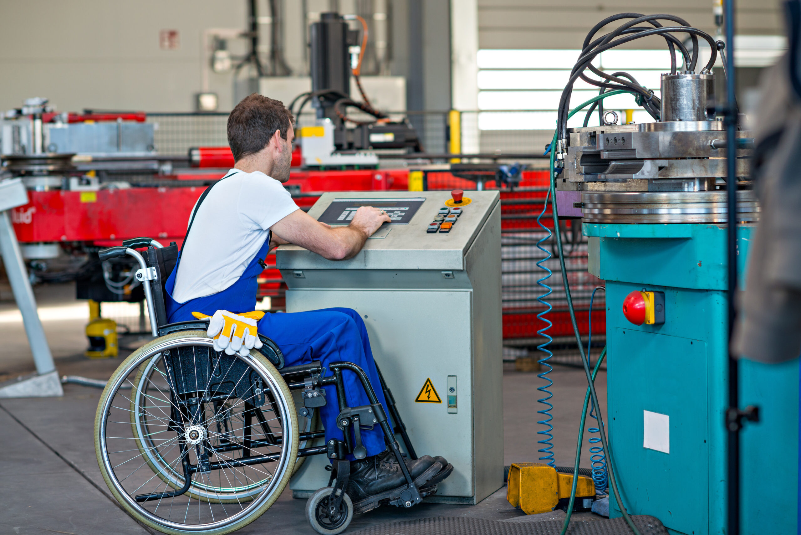Worker with a disability operating a machine in a factory from his wheelchair.